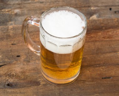 Light bira bir karanlık vintage ahşap kurullarında köpük bardak