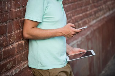 Kullanarak mobil akıllı telefon ve tablet, arka plan tuğla duvar biri yakın çekim