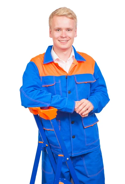 Retrato de jovem feliz de uniforme em pé perto da escada, isolado no fundo branco — Fotografia de Stock