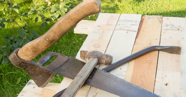 建筑工具锤子 钢锯架 躺在花园的灯板上 — 图库照片