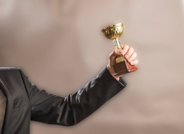 İş adamı şampiyonun altın kupasını, başarı ve zafer konseptini elinde tutar..