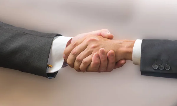 Close Handshake Dois Parceiros Negócios Ternos Fundo Cinza — Fotografia de Stock