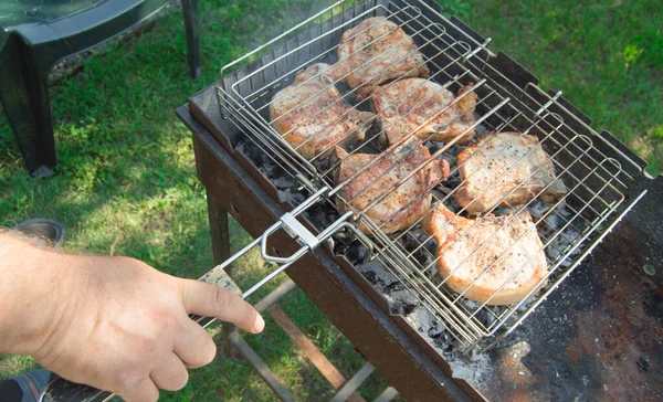 草を背景に 夏には屋外で 揚げ肉を準備する男の手のクローズアップ — ストック写真