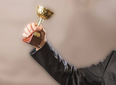 İş adamı şampiyonun altın kupasını, başarı ve zafer konseptini elinde tutar..