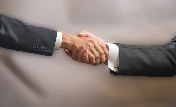 Close Handshake Dois Parceiros Negócios Ternos Fundo Cinza — Fotografia de Stock