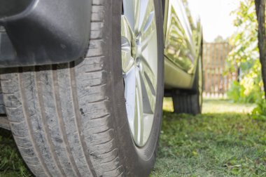 Otoparkta, çimlerin üzerinde, arka tekerlek yakın plan. Seçici odak, açık hava, yaz.