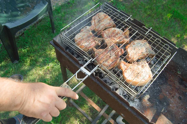 草を背景に 夏には屋外で 揚げ肉を準備する男の手のクローズアップ — ストック写真