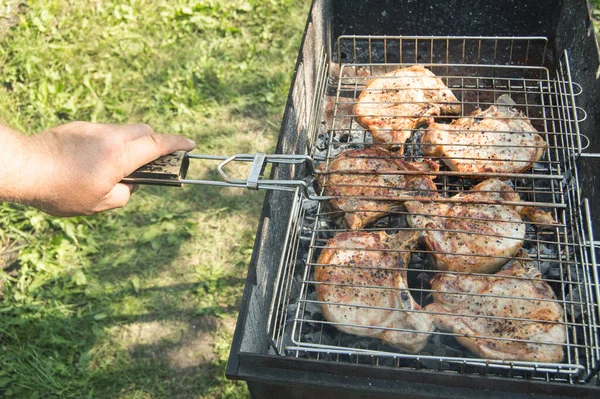 草を背景に 夏には屋外で 揚げ肉を準備する男の手のクローズアップ — ストック写真