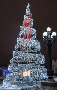 Metal inşaattan yapılmış şenlikli yaratıcı Noel ağacı kurşun lamba ve şehir fenerinin parlayan ışıkları, geceleri, açık havada..