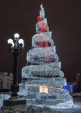 Metal inşaattan yapılmış şenlikli yaratıcı Noel ağacı kurşun lamba ve şehir fenerinin parlayan ışıkları, geceleri, açık havada..