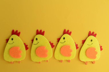 Mutlu Paskalya ev dekorasyonu konsepti. Keçeden yapılmış dört tatlı tavuk. Basit yaratıcı diy fikir, kopyalama alanı, sarı kağıt arkaplan.