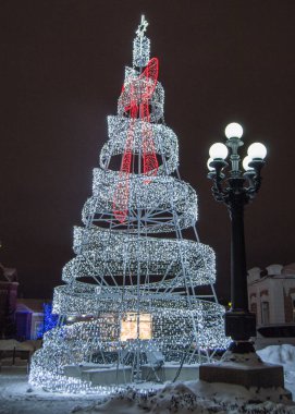 Metal inşaattan yapılmış şenlikli yaratıcı Noel ağacı kurşun lamba ve şehir fenerinin parlayan ışıkları, geceleri, açık havada..