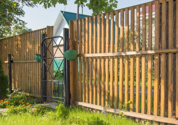Nouvelle clôture de piquet en bois avec portes métalliques, le concept de sécurité et de protection d'une maison de campagne — Photo