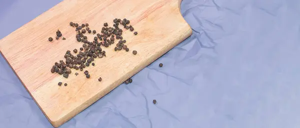 Zwarte pepererwten op een houten snijplank, bovenaanzicht, specerijen, banner — Stockfoto