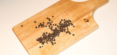 Bezelyeler beyaz arka planda, açık ahşap bir tahtaya saçılmış.