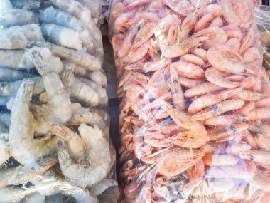 İki büyük plastik torba donmuş çiğ ve pişmiş karides, balık pazarının tezgahında.