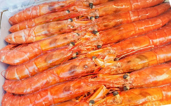 Grandes langoustines congelées dans un emballage sur le comptoir d'un marché aux poissons, gros plan — Photo