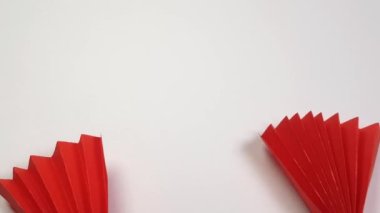 Renkli origami kağıdı beyaz arka planda kırmızı bir fan gibi görünüyor. Çin Yeni Yıl tatili geçmişi, yaratıcılık, üst görünüm, 4K video.