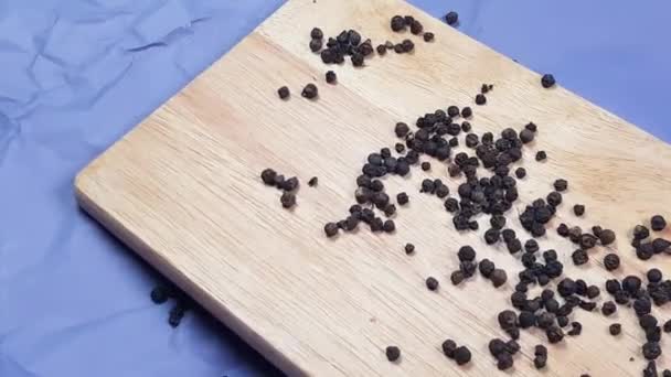 Les Pois Poivrons Noirs Roulent Sur Une Planche Découper Bois — Video