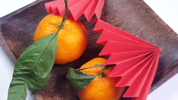 Roterande Mörk Träplatta Med Röda Origami Pappersfans Och Tangeriner Kinesiska — Stockvideo