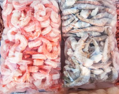 İki büyük plastik torba donmuş çiğ ve pişmiş karides, balık pazarının tezgahında..