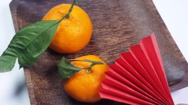 Bir el, kırmızı origami kağıt vantilatörlerini siyah ahşap bir mandalina tabağına yerleştirir. Şenlikli arka plan Çin Yeni Yılı, yaratıcılık 4K video