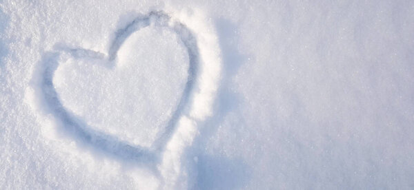 Heart shape drawn on snow closeup, Valentine day background.