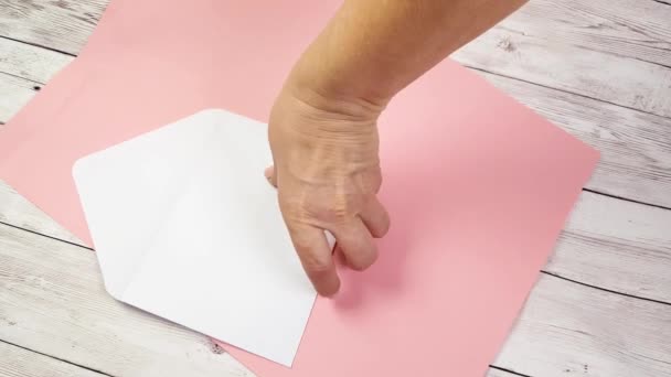 En kvinna händer sätta en röd hjärta formade Valentine kort i ett vitt kuvert för att skicka en bekännelse till en lycklig Alla hjärtans dag eller en speciell födelsedag fest med kärlek — Stockvideo