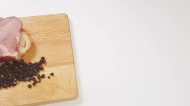 Yavaş çekim 4k video, beyaz arkaplanda ekmek, jambon ve karabiber ile kesim tahtası
