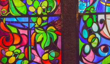 Çiçek ve meyve süslemeleri ile çok renkli camların soyut arka planına sahip iki dikey vitray pencere..