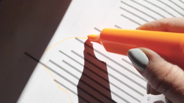 Close-up van een vrouw die een diagram tekent met een oranje stift. De vrouwelijke hand schrijft de strategie en de groeiende pijl op de kaart. Business Diagram marker tekening macro op wit papier — Stockvideo