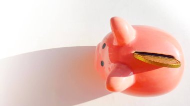 Üst görünüm pembe domuz kumbarası üzerinde slot ve eklenmiş bozuk para, beyaz arka plan, tasarruf ve yatırım konsepti, kopyalama alanı, metin için boşluk.