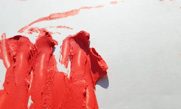 Konsistensen av utsmetat rött läppstift på en vit bakgrund, begreppet skönhet och makeup — Stockfoto