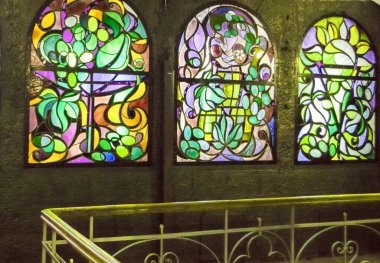 Arka arkaya lekeli cam pencereler ve merdiven, çok renkli cam sanatı pencereleri olan antika bir oda..