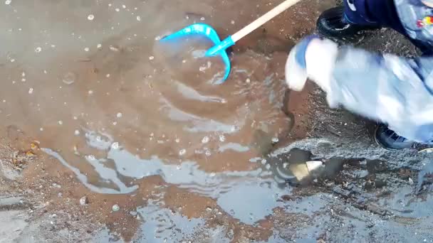 4K视频 孩子们穿着橡胶靴和夹克 在院子里玩着铲子 在泥泞的水坑里玩着雪和冰 — 图库视频影像