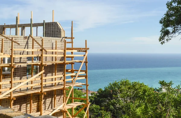 Construction of a private house or hotel on the beach, construction of walls, scaffolding, sunny summer day.