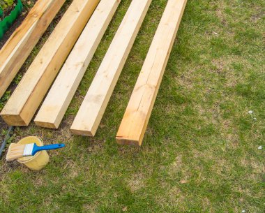 Yeni ahşap tahtaları boyamak için hazırlanırken çimlerin üzerinde, boya fırçalı bir teneke kutunun yanında, açıkta.