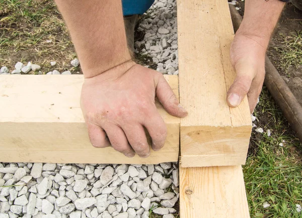 Primer plano de las manos masculinas ásperas utilizando madera nueva para el trabajo, al aire libre —  Fotos de Stock