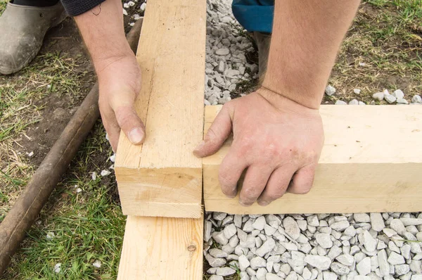 Primer plano de las manos masculinas ásperas utilizando madera nueva para el trabajo, al aire libre —  Fotos de Stock