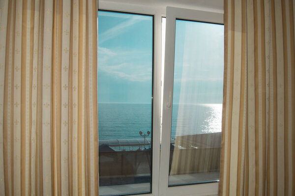 Curtains on the window, sea view at sunset, silver path, summer evening.