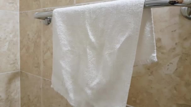 4k видео, белое махровое полотенце висит в ванной комнате на металлическом держателе полотенца — стоковое видео
