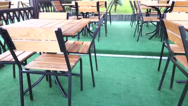 Медленное движение камеры в пустом уличном кафе мимо деревянных столов и стульев и зеленого ковра, 4 к видео — стоковое видео