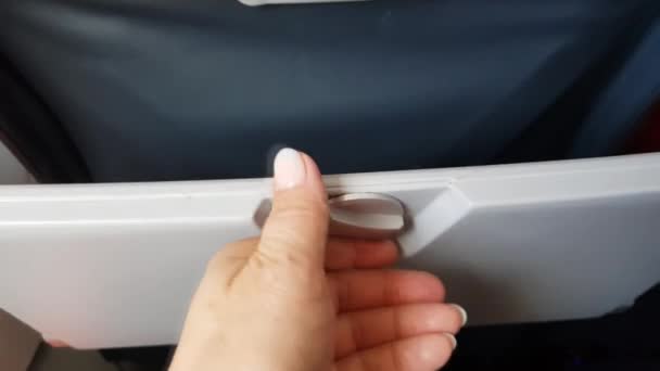 A fechadura da mesa da bandeja do avião. Close-up de um passageiro mão abrindo e fechando uma mesa de bandeja de assento de avião, vídeo 4k — Vídeo de Stock