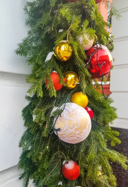 挂在冷杉枝上的圣诞球 垂直的节日花环 墙的后面 室外的建筑物装饰 — 图库照片