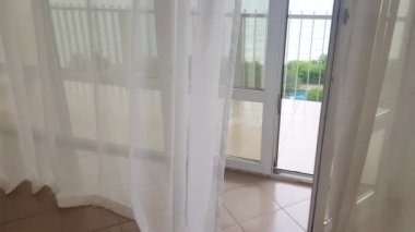 4k video, balkon ve deniz manzarası şeffaf perdelerin arasından rüzgar şeffaf perdeleri sallıyor, deniz manzaralı bir otel.