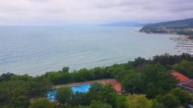 4k video, Gündoğumu, deniz bulutlarının manzarası, deniz kıyısında bir körfez ve bir kasaba, arka planda dağ siluetleri belirdi.