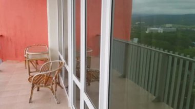 4k video, panoramik pencereli modern bir otel balkonunda hasır mobilya.