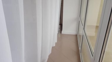 4k video, kameranın balkondaki beyaz naylon perde boyunca yavaşça hareket etmesi.