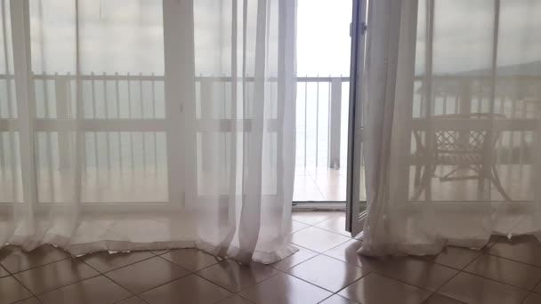 4k vídeo, vista da varanda e do mar através de cortinas transparentes, o vento balança as cortinas transparentes, um hotel com vista para o mar — Vídeo de Stock