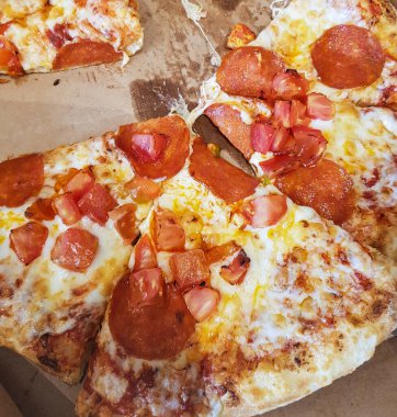 Dilimlenmiş pizza, karton bir kutunun içinde, üst tarafta..